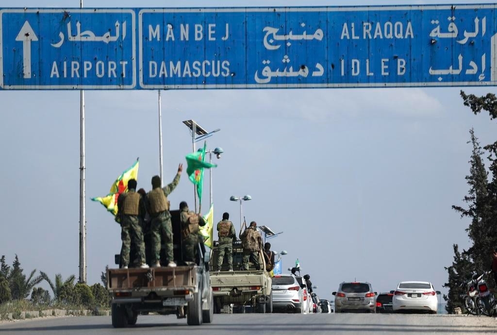 Курдские бойцы стоят на своих машинах во время вывода войск из двух районов Алеппо в рамках соглашения с сирийским центральным правительством