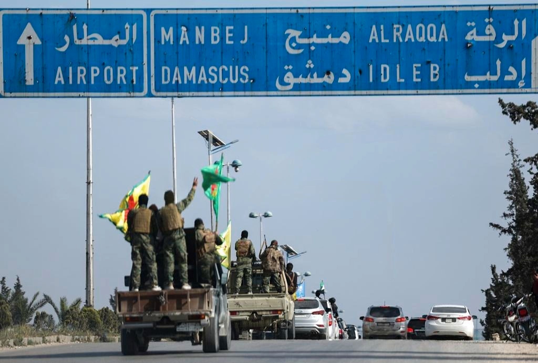 Kurdish fighters stand on their vehicles during a withdrawal from two Aleppo districts under an agreement with the central government.