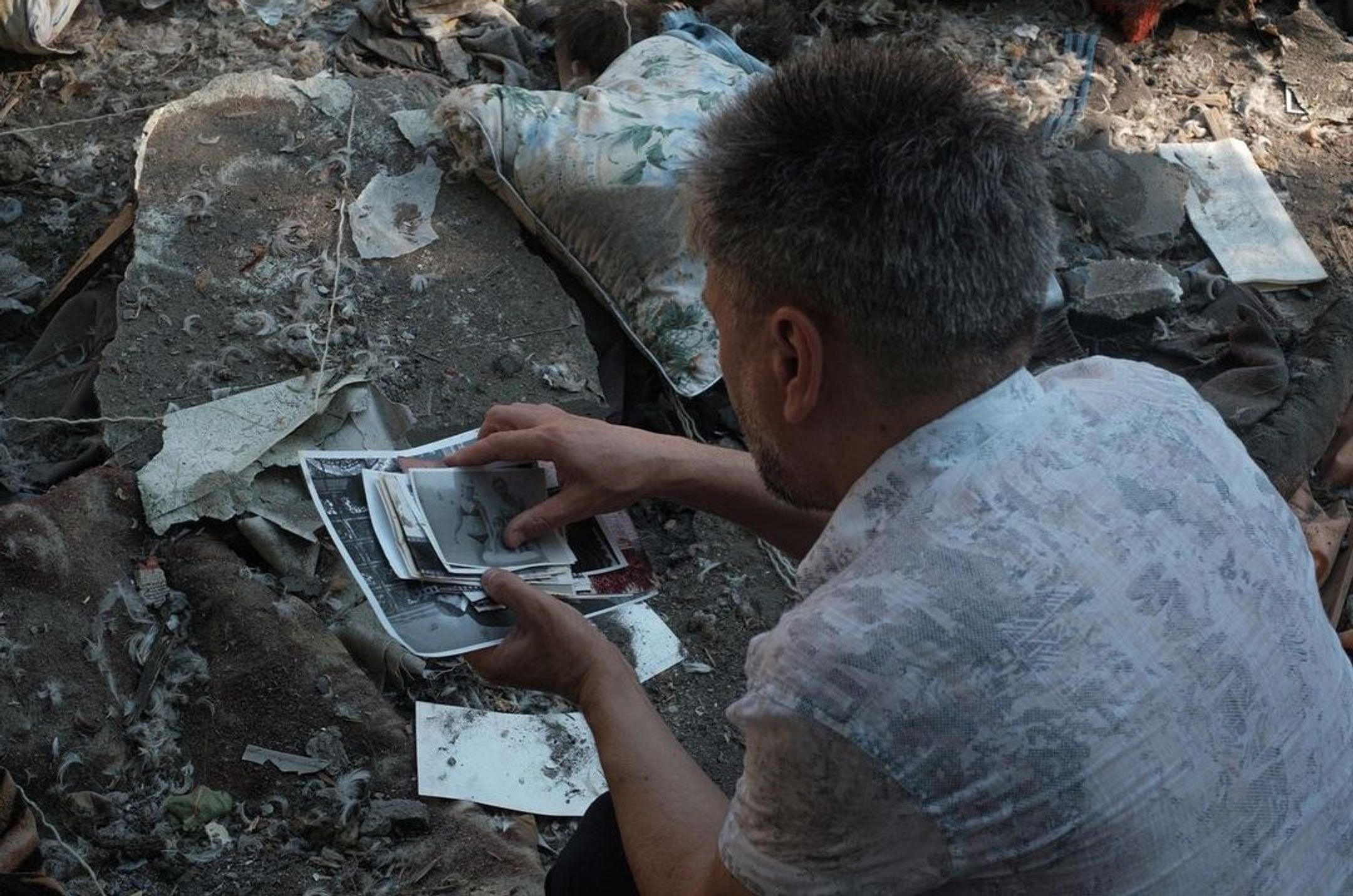 A man collects photographs of his relatives scattered near the destroyed five-story building, Mykolaiv