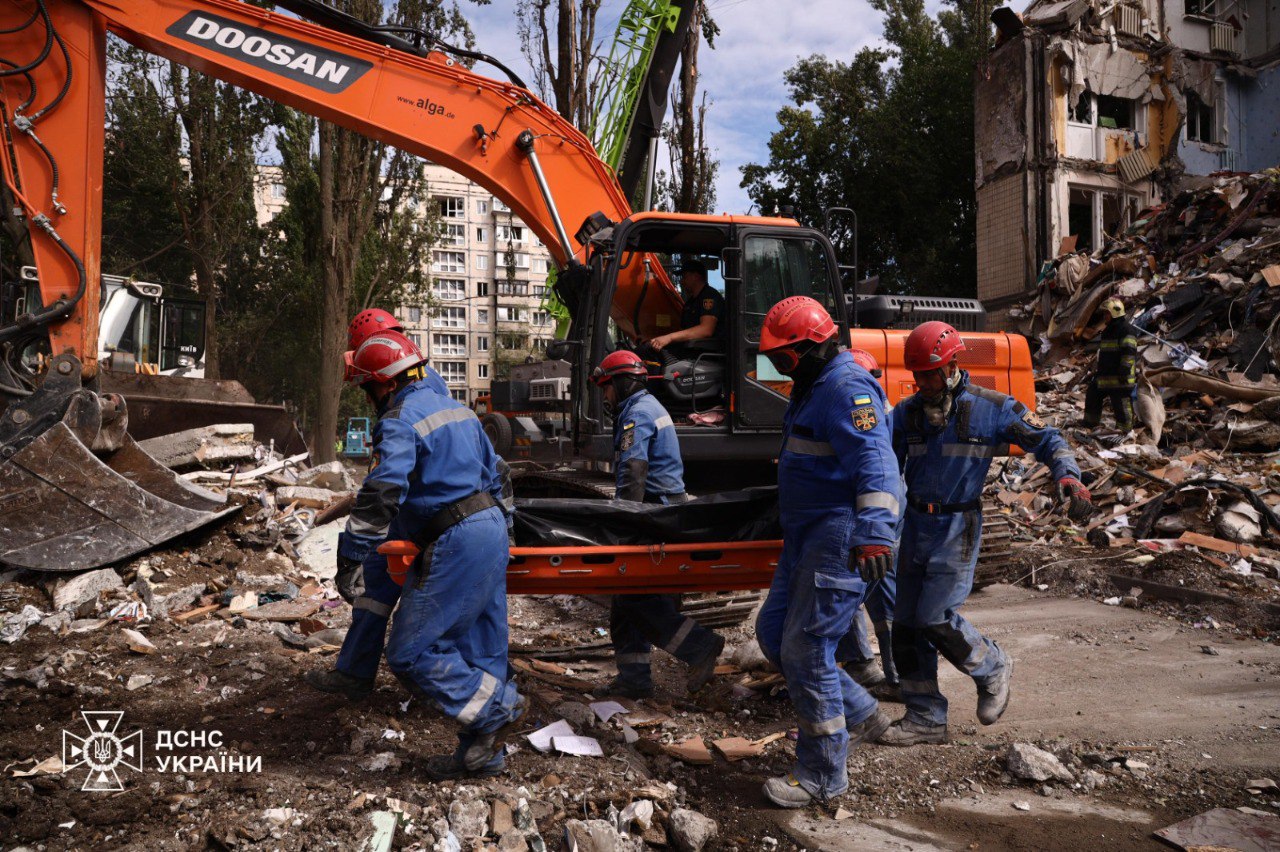 Rescue workers carry a body pulled out from under the rubble of.a residential building in Kyiv. Photo: State Emergency Service of Ukraine